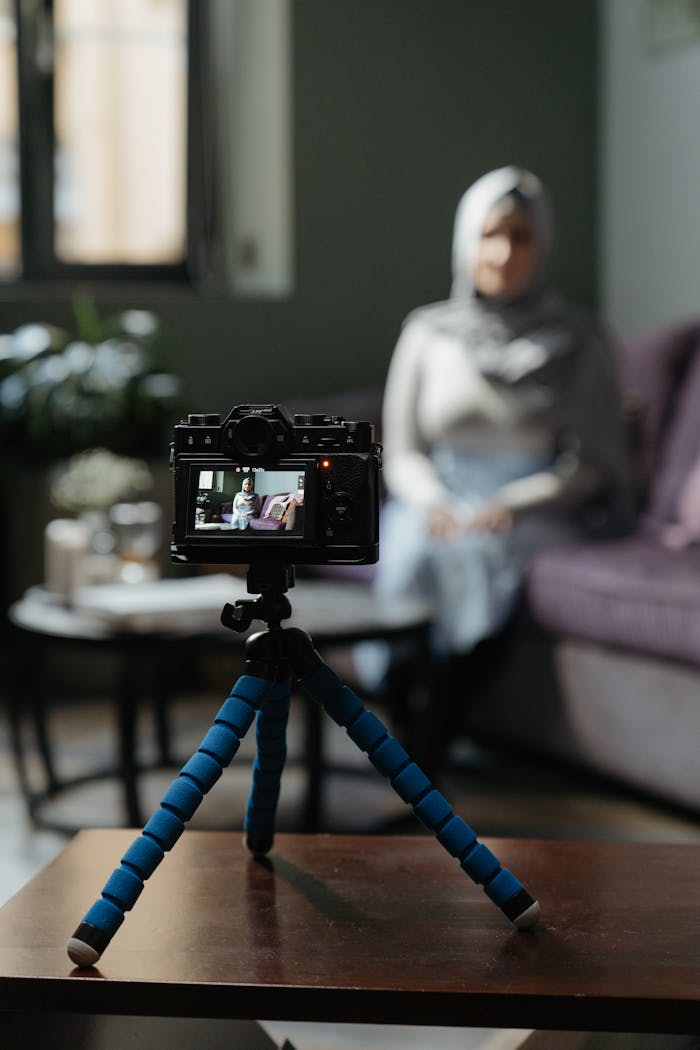 Camera on a tripod filming a woman in a cozy living room setting for a vlog.